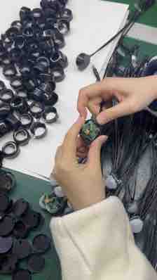 Hands assembling round sensor modules at a factory workstation